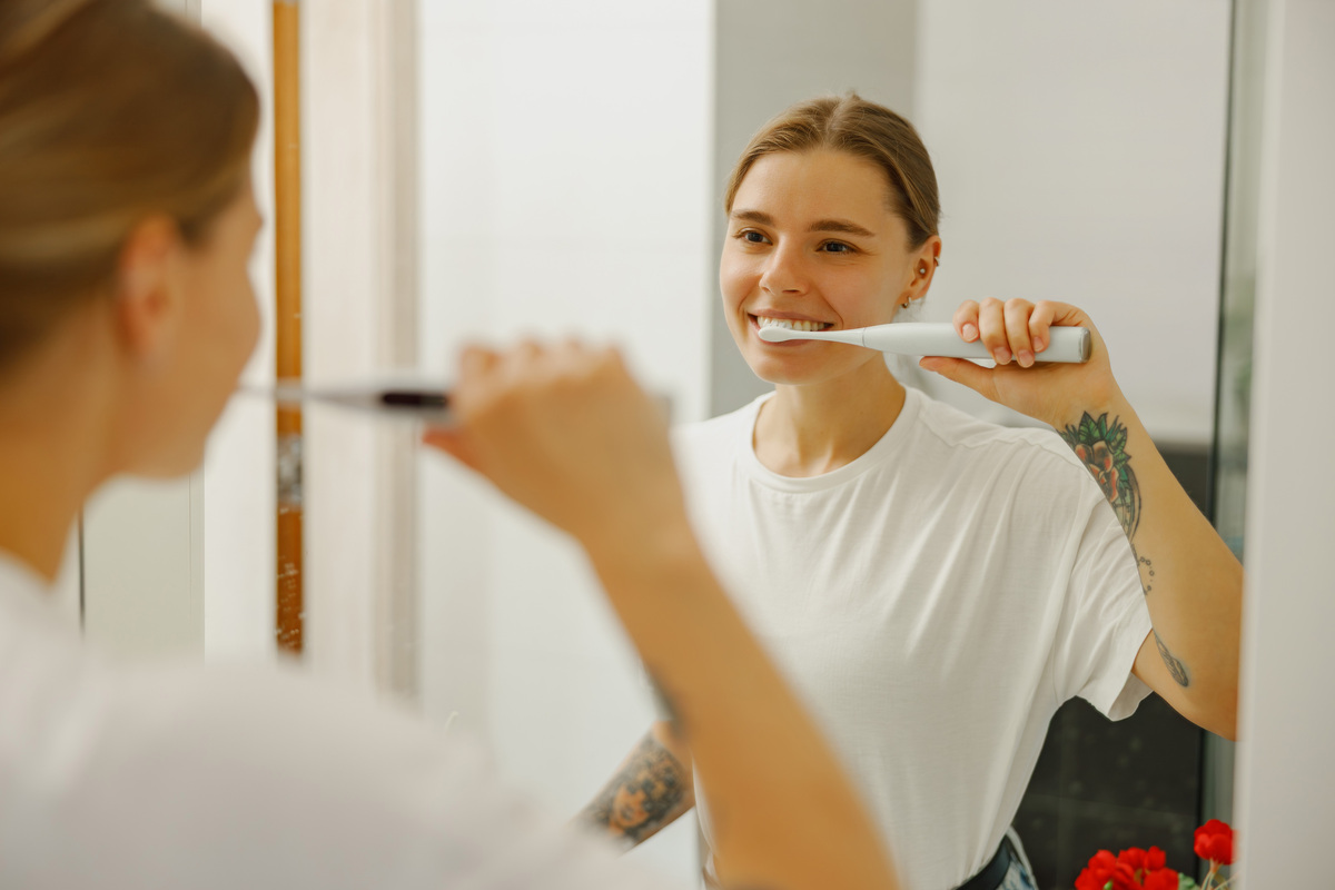 Woman brushing teeth to protect dental bridge daily